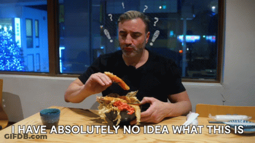 A Man Sitting At A Table Eating Food With The Words I Have Absolutely No Idea What This Is GIF
