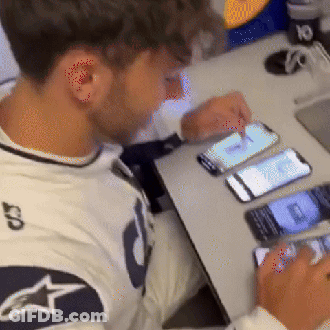 A Man Sitting At A Table Looking At A Cell Phone With The Number 10 On It GIF
