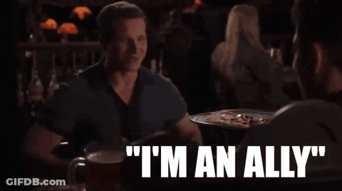A Man Sitting At A Table Says " I 'M An Ally " While Talking To Another Man GIF