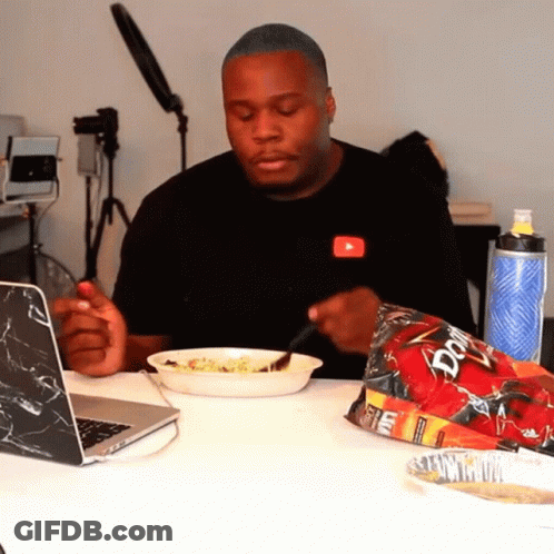 A Man Sitting At A Table With A Bag Of Doritos GIF