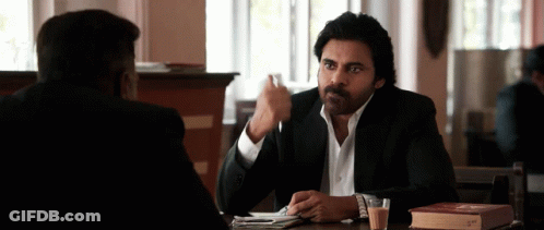 A Man Sitting At A Table With A Book On It GIF