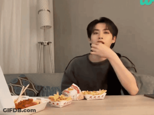A Man Sitting At A Table With A Box Of Wendy 'S French Fries On It GIF
