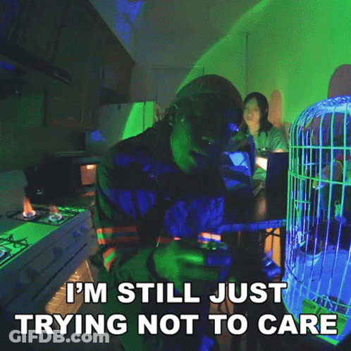 A Man Sitting At A Table With A Cage In The Background And The Words I 'M Still Just Trying GIF