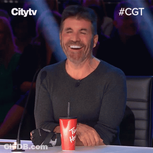 A Man Sitting At A Table With A Cup That Says Tim Hortons GIF