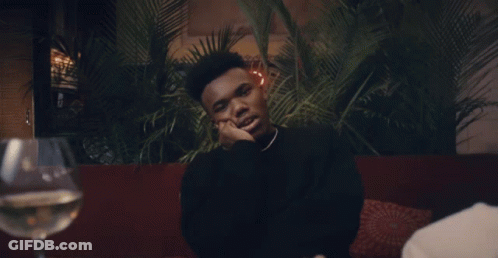 A Man Sitting At A Table With A Glass Of Wine GIF