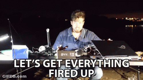 A Man Sitting At A Table With A Laptop And A Sign That Says 8:44 GIF