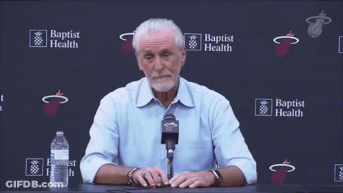 A Man Sitting At A Table With A Microphone In Front Of A Wall That Says Baptist Health GIF