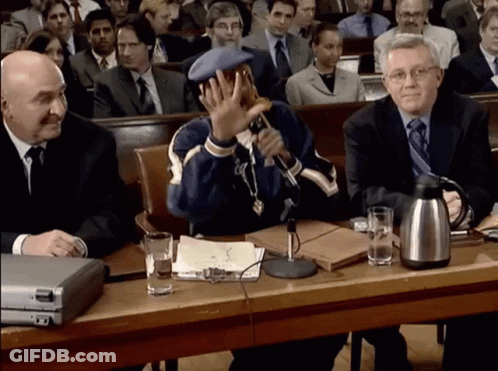 A Man Sitting At A Table With A Microphone In Front Of Him GIF