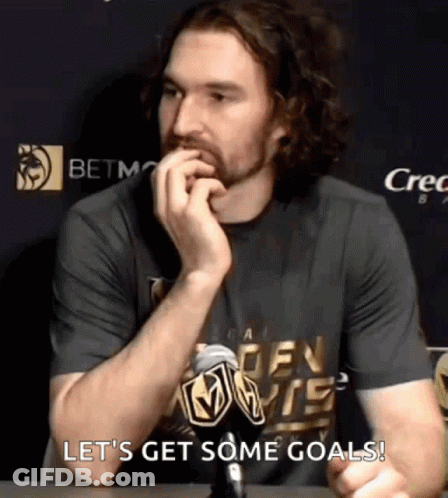A Man Sitting At A Table With A Microphone In His Hand And The Words Let 'S Get Some Goals Behind Him GIF