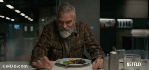 A Man Sitting At A Table With A Plate Of Food And A Netflix Logo On The Bottom GIF