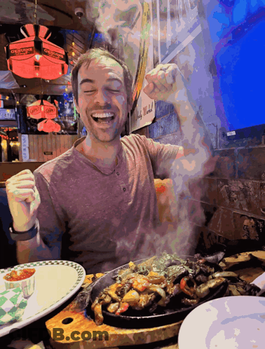 A Man Sitting At A Table With A Plate Of Food And A Sign That Says Georges On It GIF