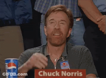 A Man Sitting At A Table With A Sign That Says Chuck Norris On It GIF