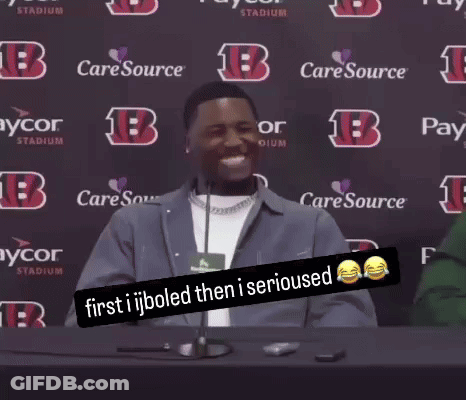 A Man Sitting At A Table With A Sign That Says " First Ijboled Then I Serious " GIF