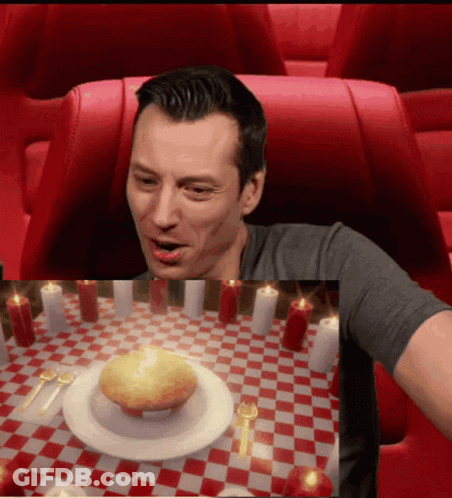 A Man Sitting At A Table With Candles And A Plate Of Food GIF