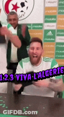 A Man Sitting At A Table With The Words 123 Viva L' Algerie GIF