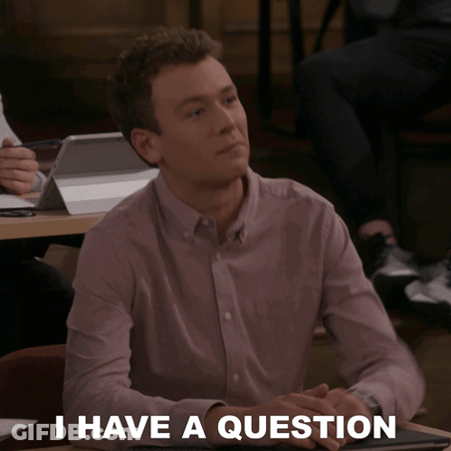 A Man Sitting At A Table With The Words " I Have A Question " On The Bottom GIF