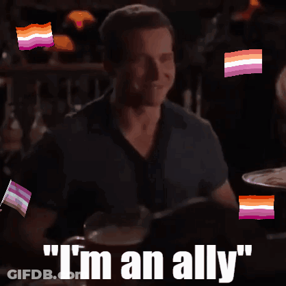 A Man Sitting At A Table With The Words " I 'M An Ally " On The Bottom GIF