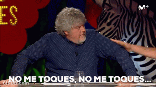 A Man Sitting At A Table With The Words No Me Toques On The Screen GIF