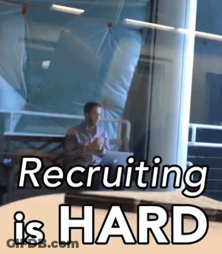 A Man Sitting At A Table With The Words Recruiting Is Hard Written On It GIF