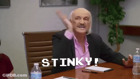A Man Sitting At A Table With The Words Stinky Written On The Screen GIF