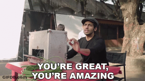 A Man Sitting At A Table With The Words " You 'Re Great You 'Re Amazing " Above Him GIF
