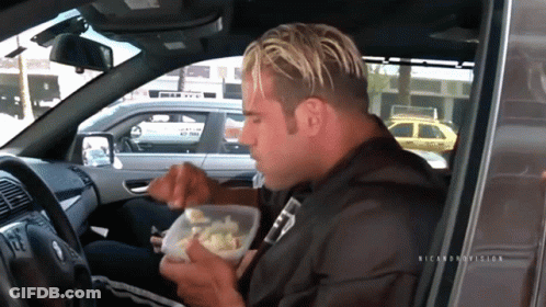 A Man Sitting In A Car Eating From A Plastic Container With The Name Ricardo On The Bottom GIF