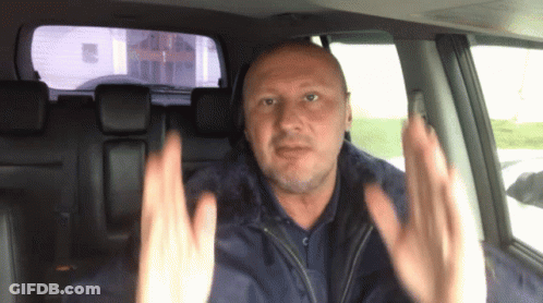 A Man Sitting In A Car With His Hands Up GIF