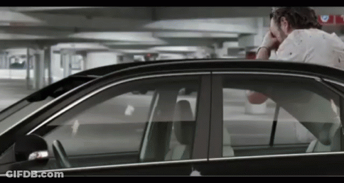 A Man Sitting In A Car With His Head In His Hand GIF