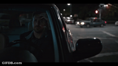 A Man Sitting In A Car With His Head In His Hand GIF