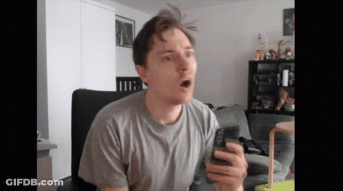 A Man Sitting In A Chair Holding A Cell Phone GIF