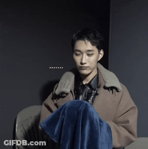 A Man Sitting In A Chair With A Blue Blanket Around His Knee GIF