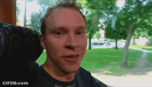 A Man Sitting In A Chair With A Blurred Background Of Trees GIF