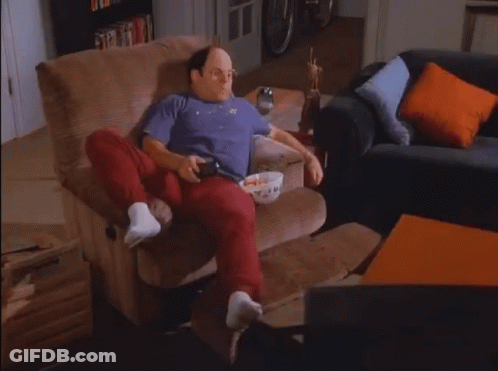 A Man Sitting In A Chair With A Bowl Of Popcorn On His Lap GIF