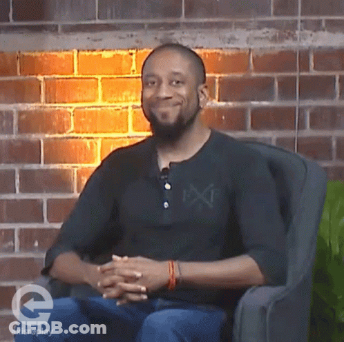 A Man Sitting In A Chair With A Brick Wall Behind Him And A Logo For Axisreplay On The Bottom GIF