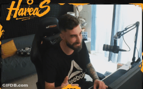 A Man Sitting In A Chair With A Reebok Shirt On GIF