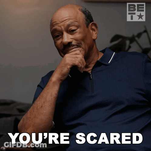 A Man Sitting In A Chair With His Hand On His Chin And The Words You 'Re Scared Below Him GIF