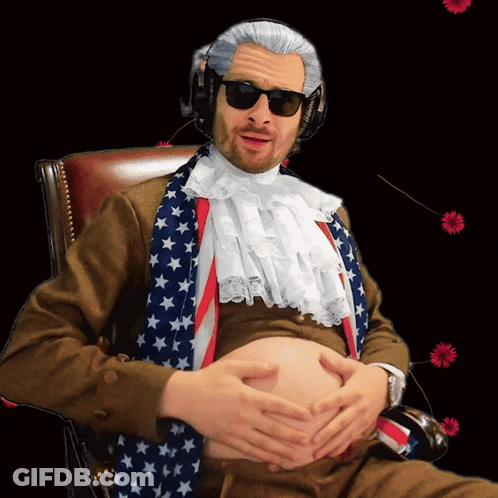 A Man Sitting In A Chair With His Hands On His Belly Wearing An American Flag Scarf GIF