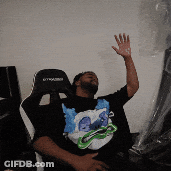 A Man Sitting In A Gtracing Chair With His Hand Up GIF