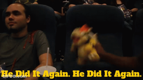 A Man Sitting In A Movie Theater Holding A Stuffed Bowser GIF