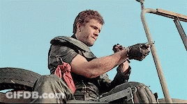 A Man Sitting In A Vehicle With A Gun In His Hand GIF