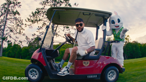 A Man Sitting In A Yamaha Golf Cart Next To A Stuffed Rabbit GIF