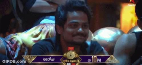 A Man Sitting In Front Of A Banner That Says Big Boss 5 At 10 Pm GIF