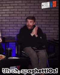 A Man Sitting In Front Of A Brick Wall With The Words Uh Oh Spaghettios On The Bottom GIF