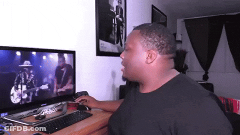 A Man Sitting In Front Of A Computer Monitor Watching A Video GIF