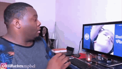 A Man Sitting In Front Of A Computer With A Picture Of A Woman On The Screen .. GIF