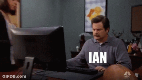 A Man Sitting In Front Of A Computer With Ian On His Shirt GIF