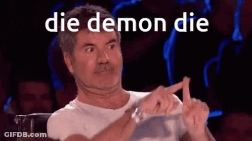A Man Sitting In Front Of A Crowd With The Words Die Demon Die On His Face GIF