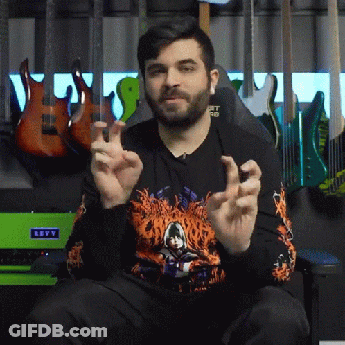 A Man Sitting In Front Of A Green Revv Amplifier GIF