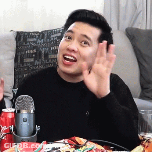 A Man Sitting In Front Of A Microphone In Front Of A Pillow That Says Milan On It GIF