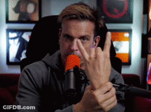 A Man Sitting In Front Of A Microphone Making A Middle Finger Gesture GIF